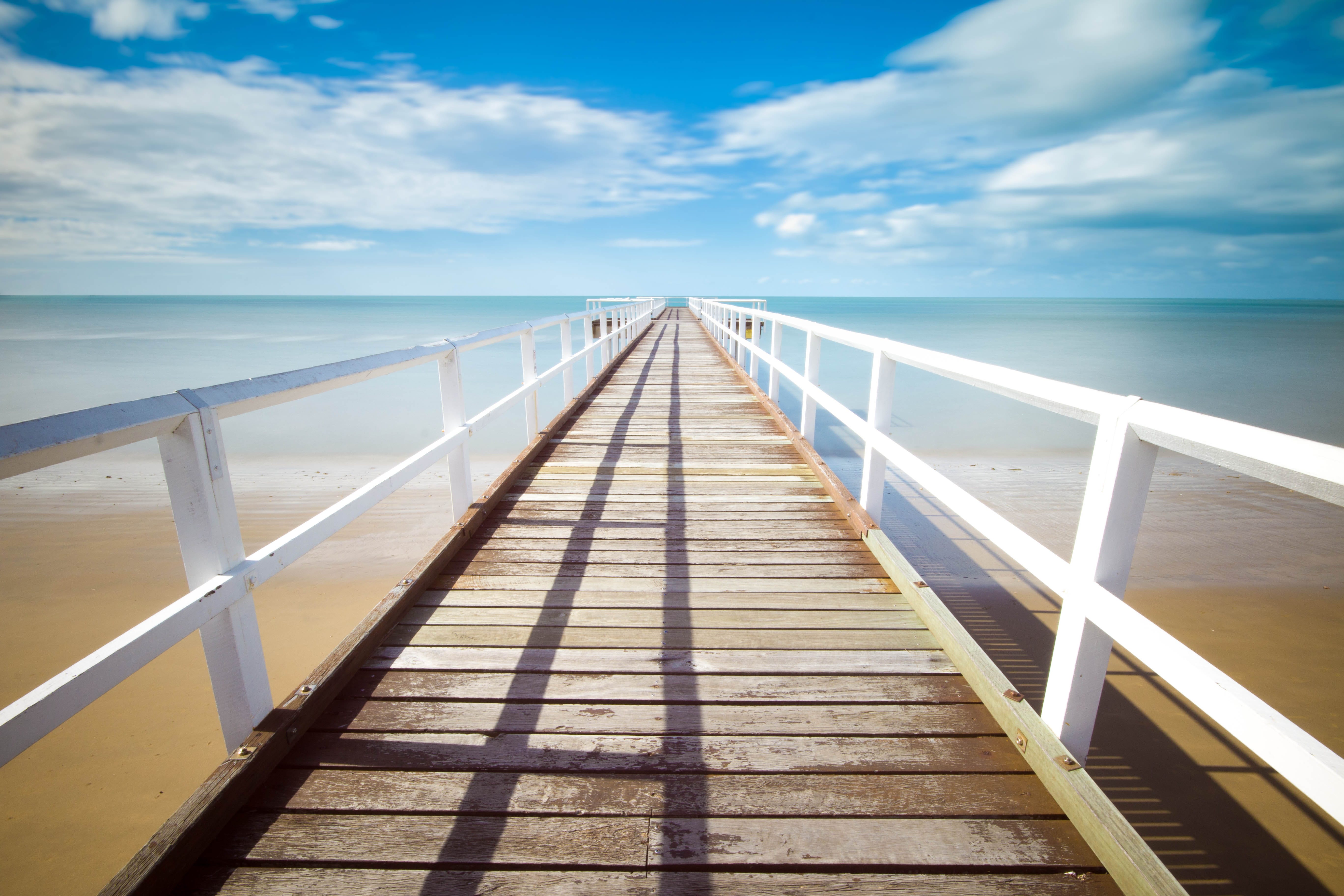 “Wooden pier pathway with white wooden railing” by Christian Holzinger on Unsplash