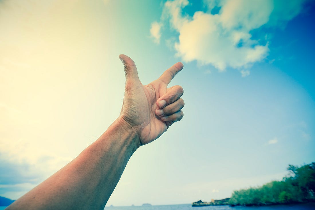 Left arm extended upward with thumb extended and forefinger pointing to a white cloud.