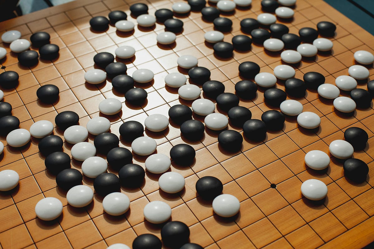 Detailed shot of a wooden Go board with black and white stones placed across the grid, illustrating an ongoing game in natural light.