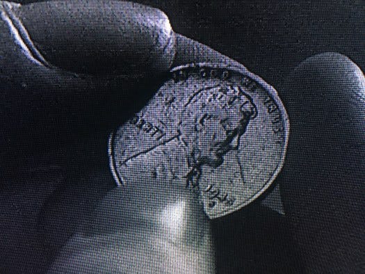Close-up of the penny in Sarah's fingers.