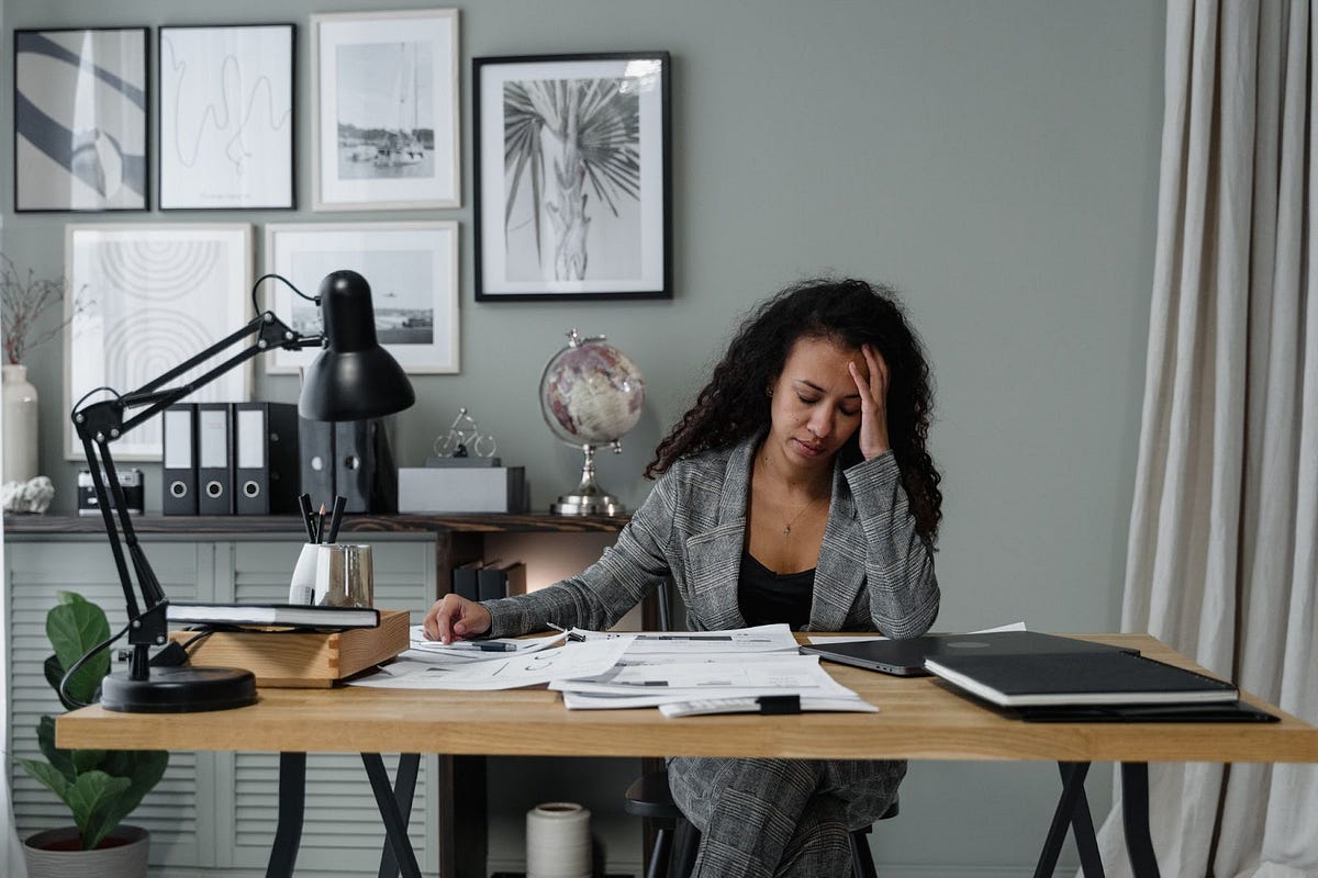 woman holding her head while working on paperwork