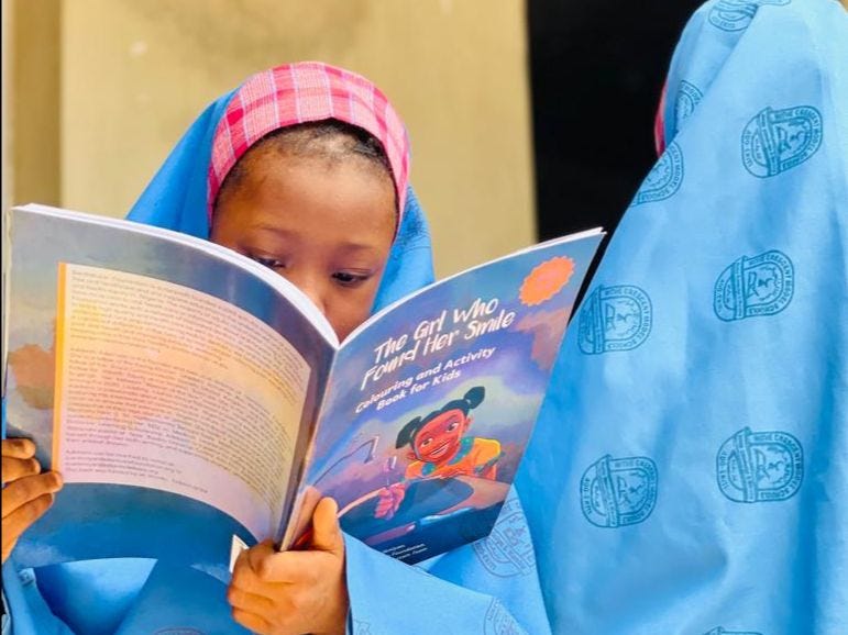 A 6 year old girl reading a copy of The Girl Who Found Her Smile.