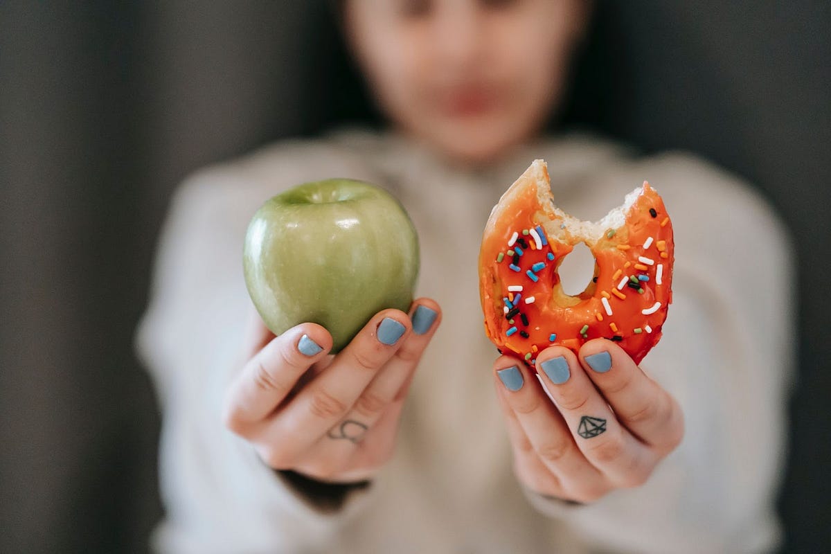 a person holding an apple and a donut