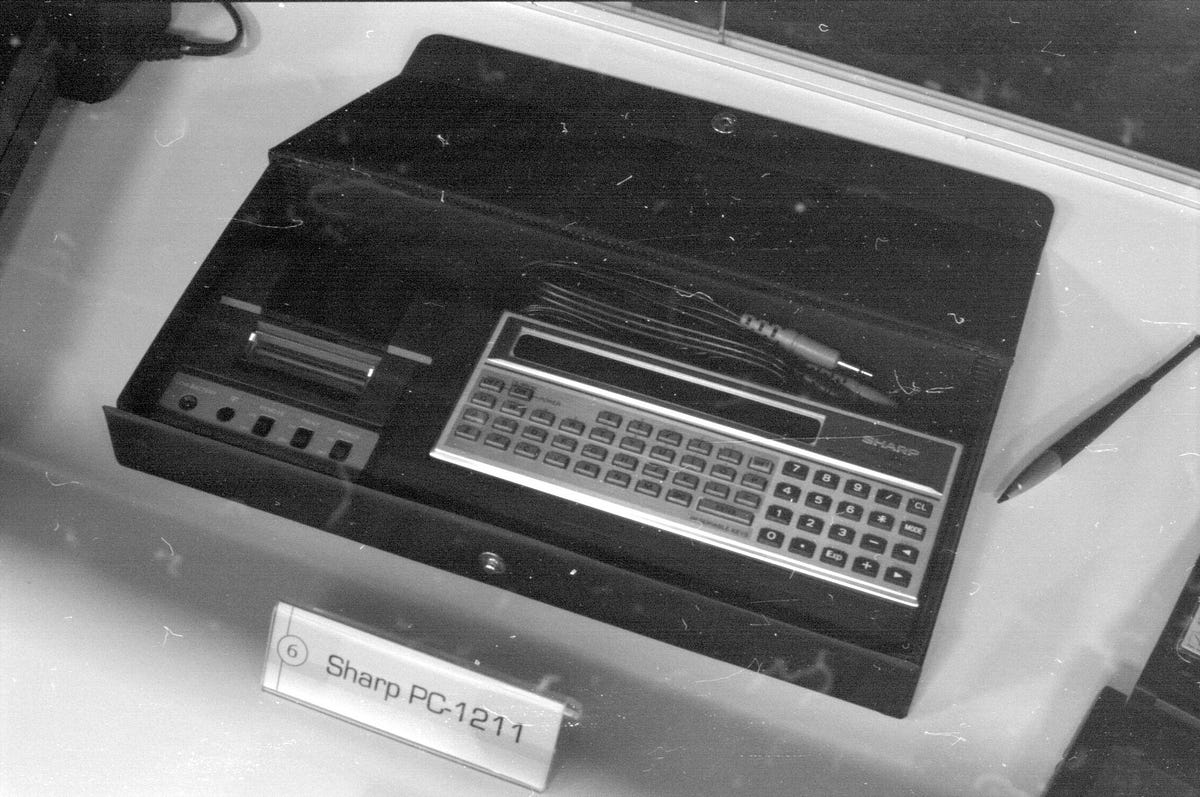 Sharp’s 1980 PC-1211, in its travel case (which also had space for a printer). This machine, rebadged as the TRS-80 by Radioshack, is the same as the one Isaac Asimov is holding at the top of this article. (Photo credit: Rama/CC BY-SA 2.0). Sharp’s 1980 PC-1211, in its travel case (which also had space for a printer). This machine, rebadged as the TRS-80 by Radioshack, is the same as the one Isaac Asimov is holding at the top of this article. (Photo credit: Rama/CC BY-SA 2.0).
