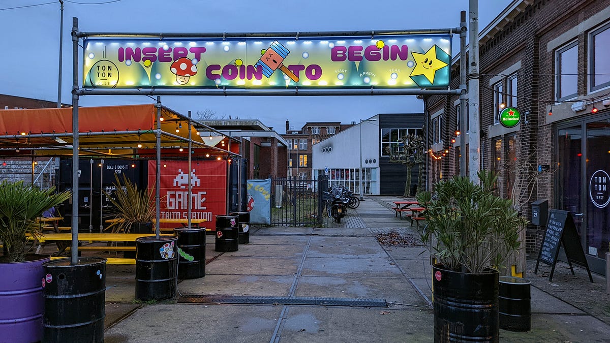 Entrance to TonTon Club with sign overhead saying ‘Insert Coin to Begin’