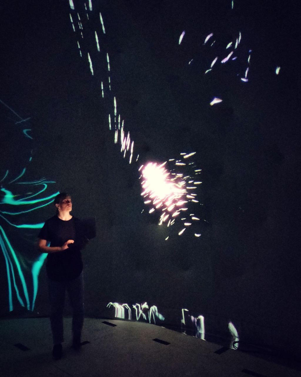 Woman in black standing in the Laila dome with projections in the background