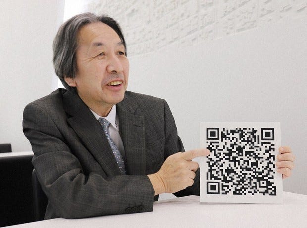 Masahiro Hara, the engineer who invented the QR code in 1994 while working at Denso Wave, holding the technology that went on to transform how the world shares information.