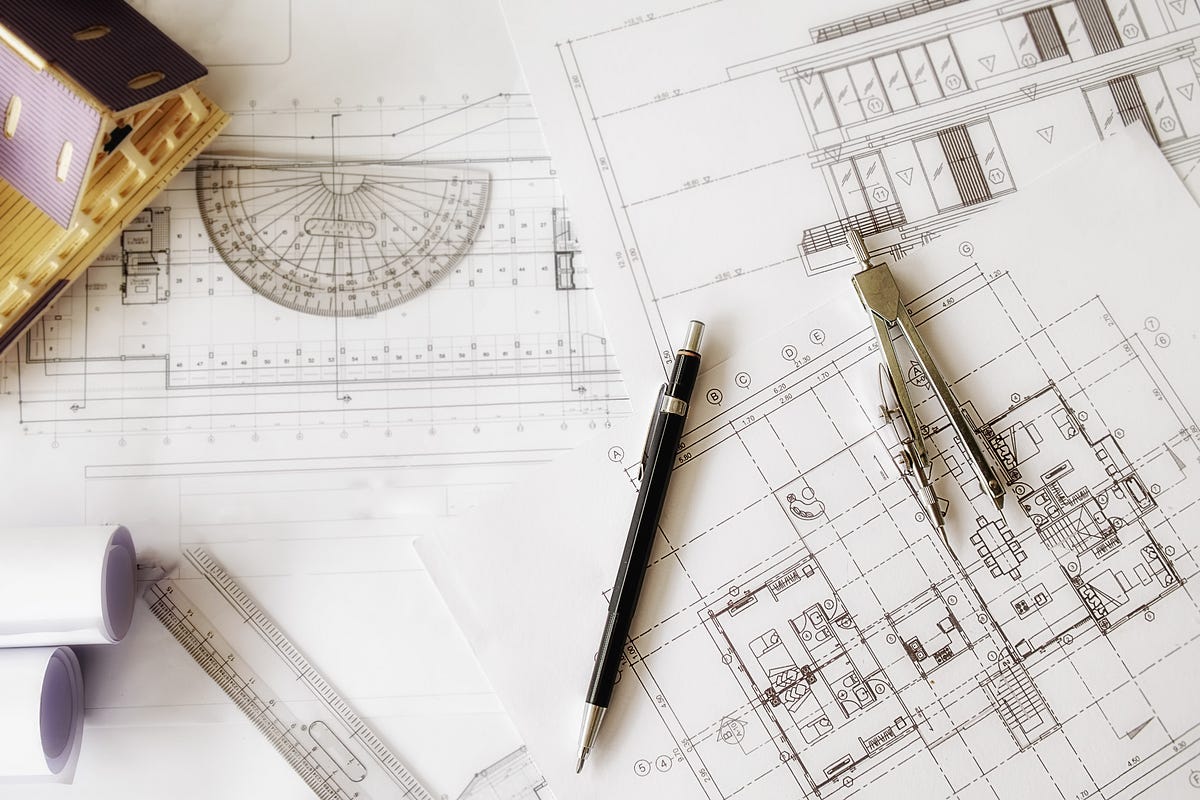 This image captures the essence of architectural creativity and precision, featuring detailed blueprints, a scale ruler, drafting compass, and mechanical pencil arranged on a designer’s workspace. The plans illustrate structural layouts and building elevations, highlighting the meticulous process behind modern construction. A perfect representation of architecture, engineering, and design innovation, it symbolizes the foundation of every great project.