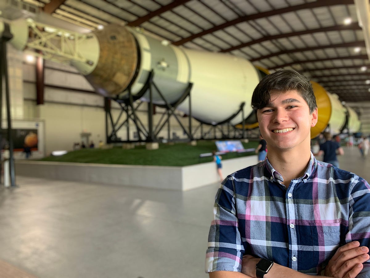 Connor Anton poses in front of a Saturn V rocket at NASA’s Johnson Space Center.