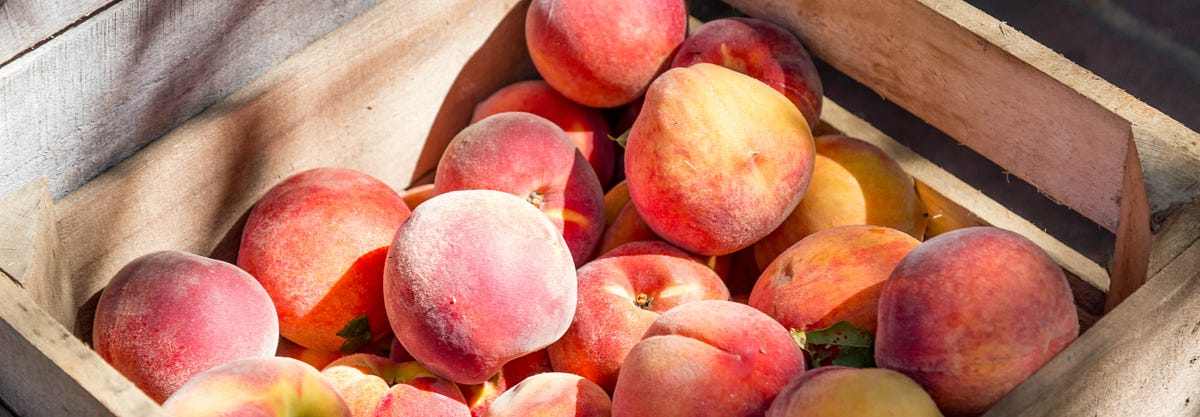 Ripe peaches in a wooden crate