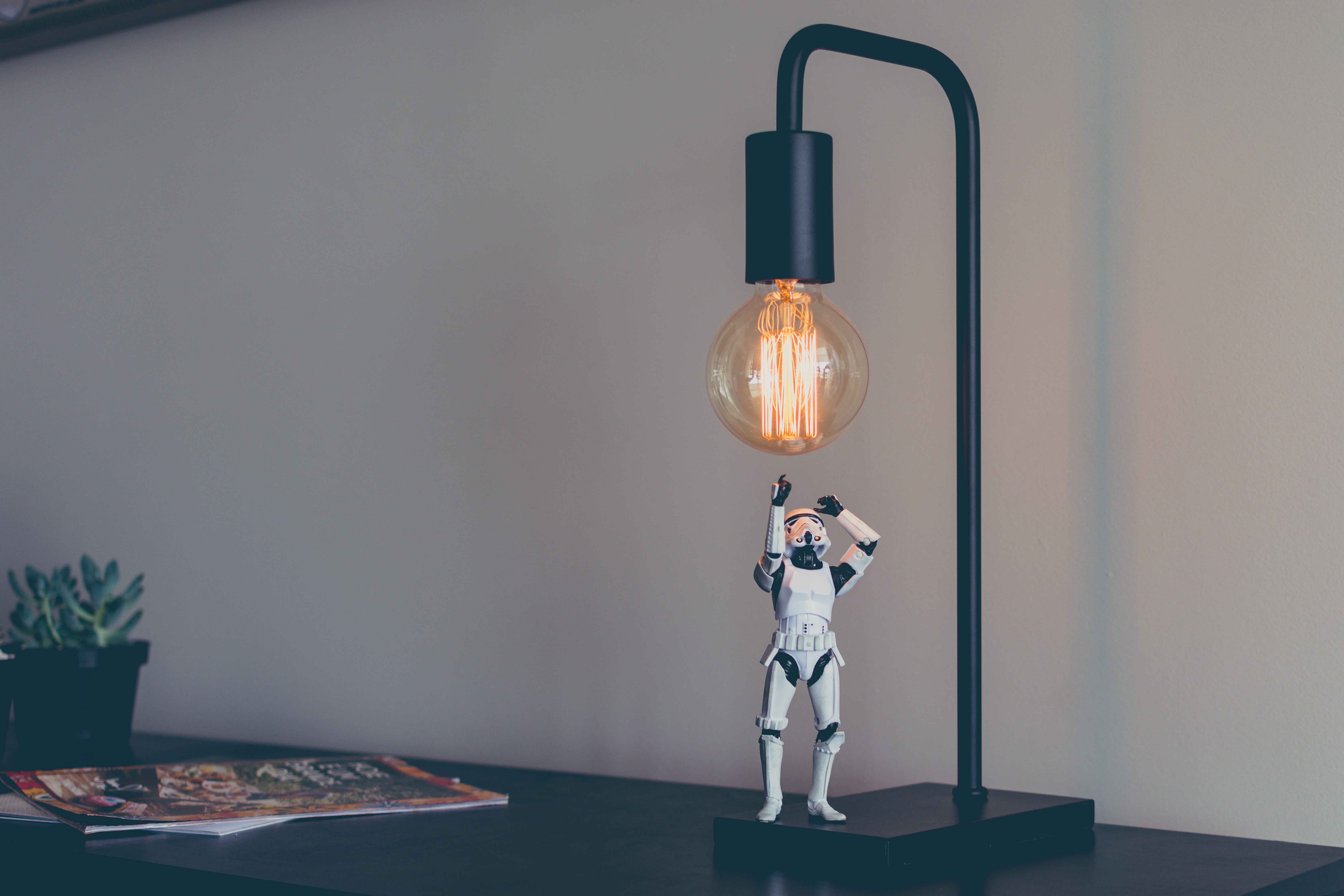 “A figurine of a stormtrooper under a desk lamp with an incandescent light bulb” by James Pond on Unsplash