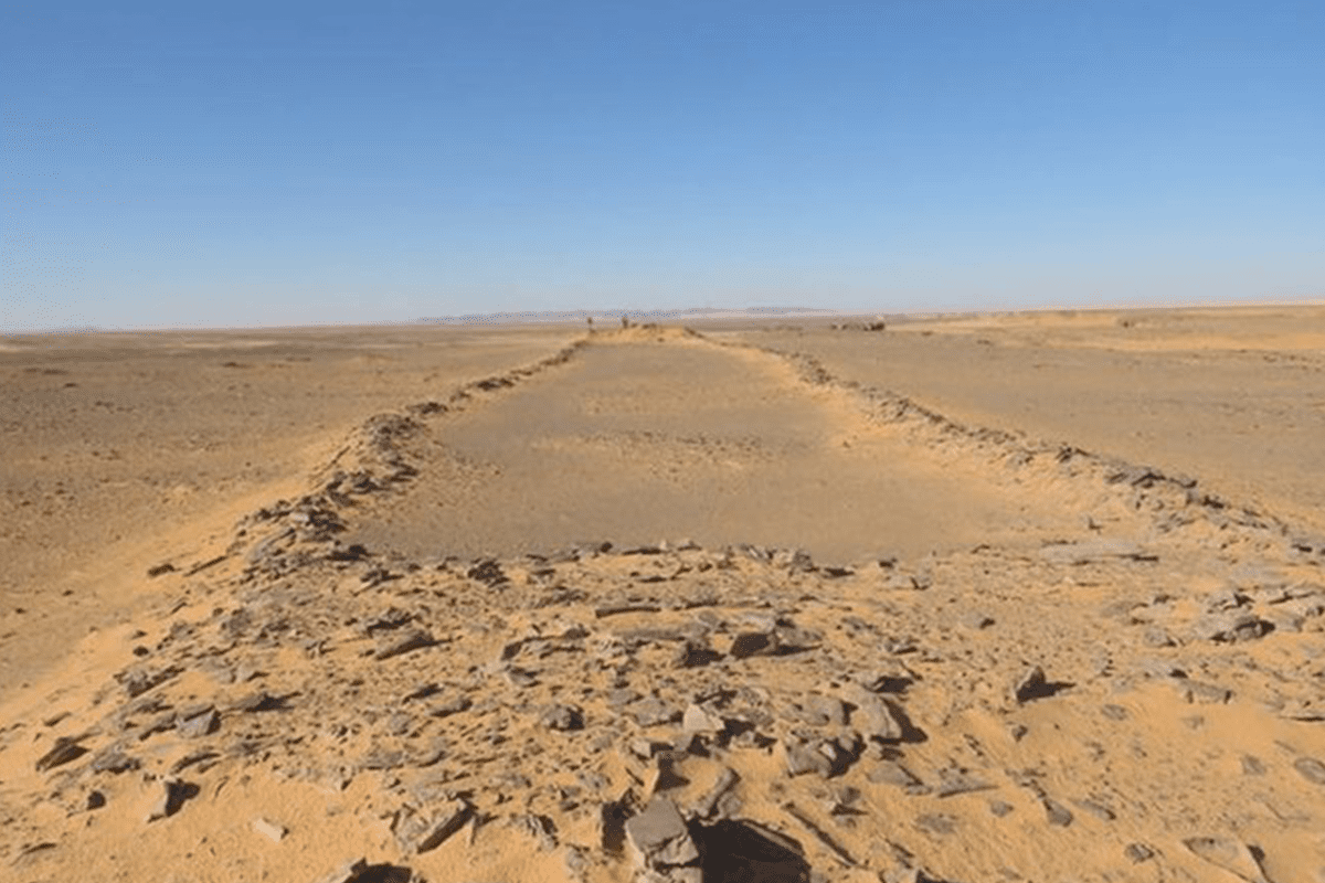 A section of desert with a very long, slightly elevated “runway” made out of weathered rocks.