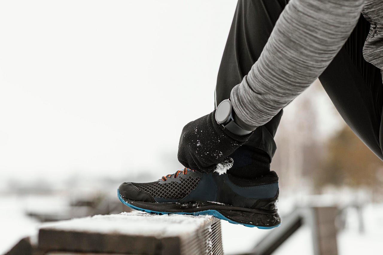 Runner tightening their snow-dusted sneakers in the crisp winter air, symbolizing motivation and perseverance during colder months. This image resonates with staying active and embracing outdoor workouts, even in challenging weather.