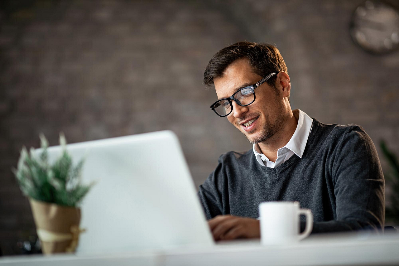 Smiling professional working on a laptop, highlighting productivity and focus in a relaxed workspace. A balanced routine and effective tools like a timer app can enhance efficiency and keep the workday smooth.