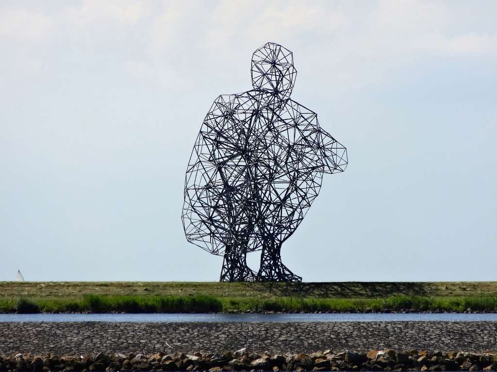 “Exposure” by Antony Gormley, a large sculpture depicting a hollow crouching person, made of straight pieces of metal bolted together.
