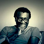 Foto do Milton — Homem negro, usa óculos de grau e sorri