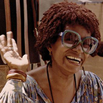 Foto da Léila — Mulher negra óculos escuro, sorri e tem cabelo preto e curto