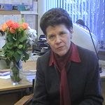 Prof Katharine Perera at her desk with vase of roses