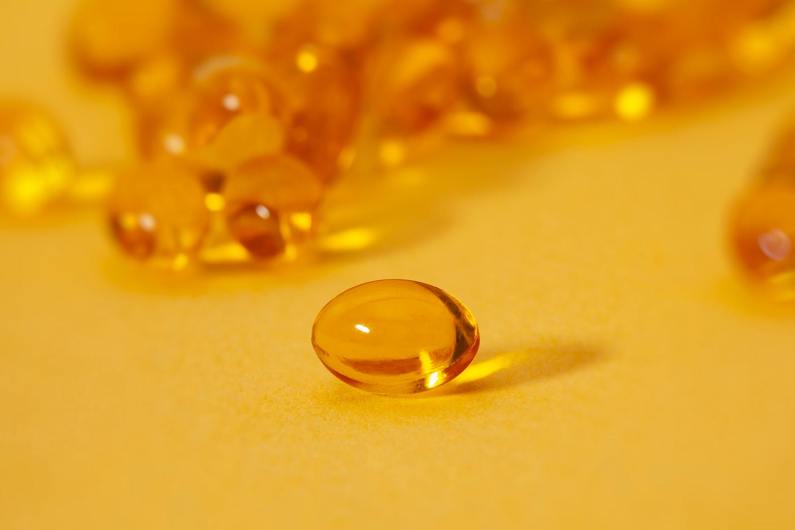 Several yellow vitamin D capsules in close-up. Vitamin D deficiency is associated with muscle loss.