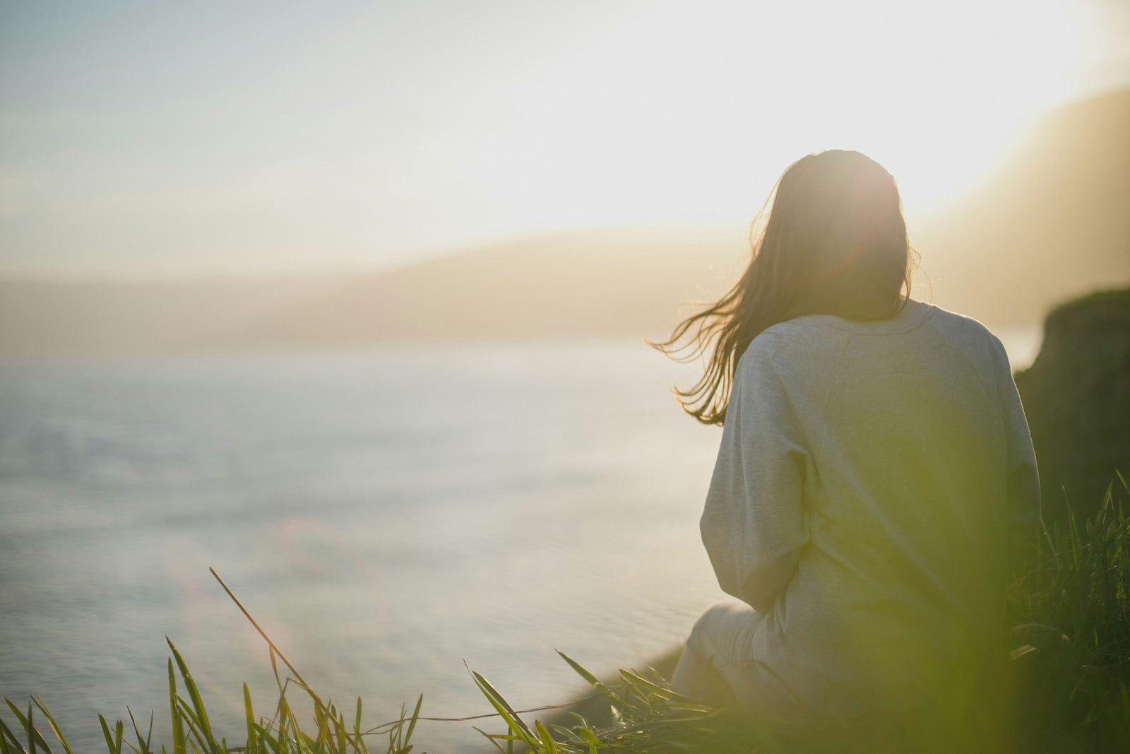 A middle-aged woman looks out at a lake.