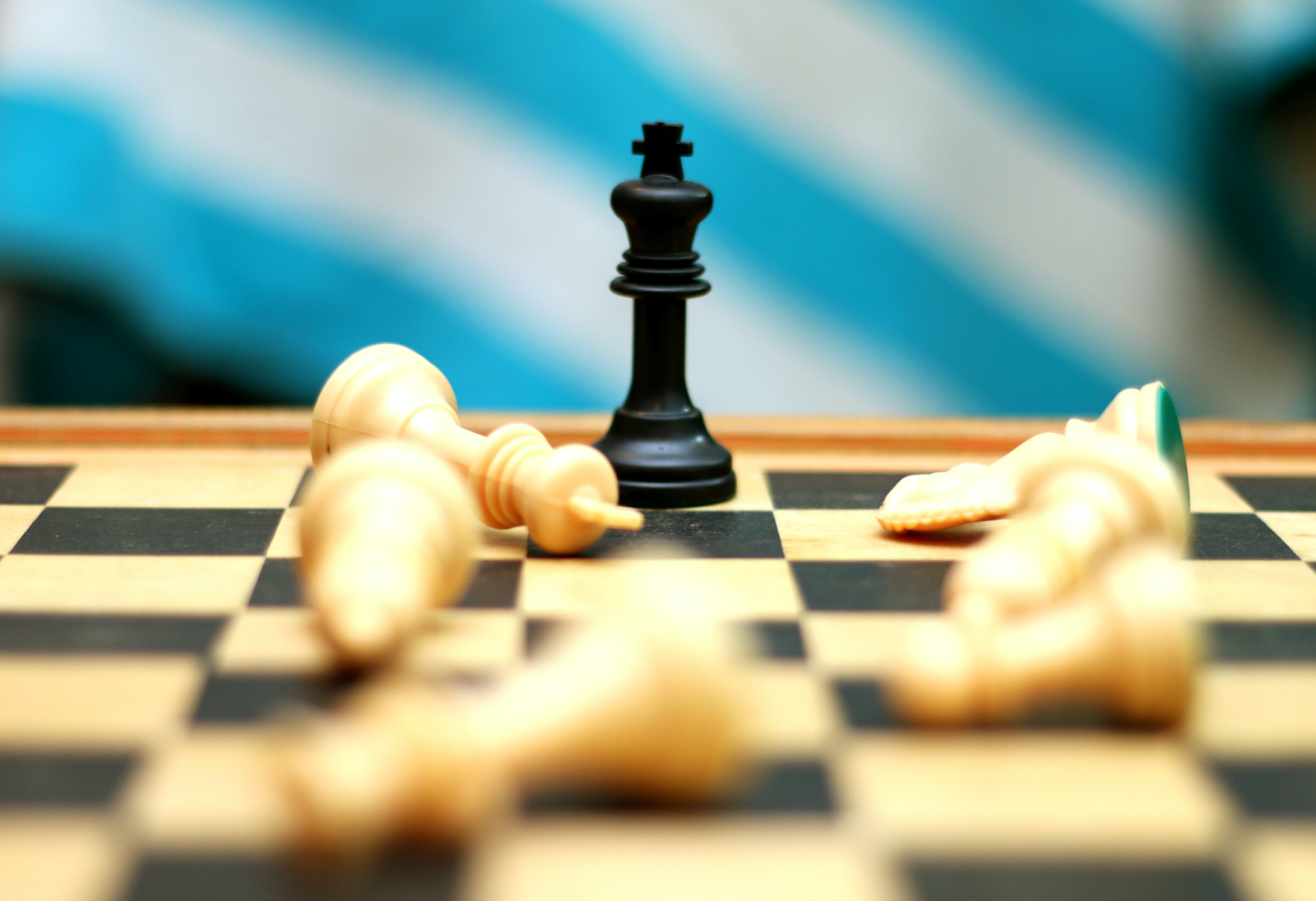 black king on chess board, white pieces fallen down