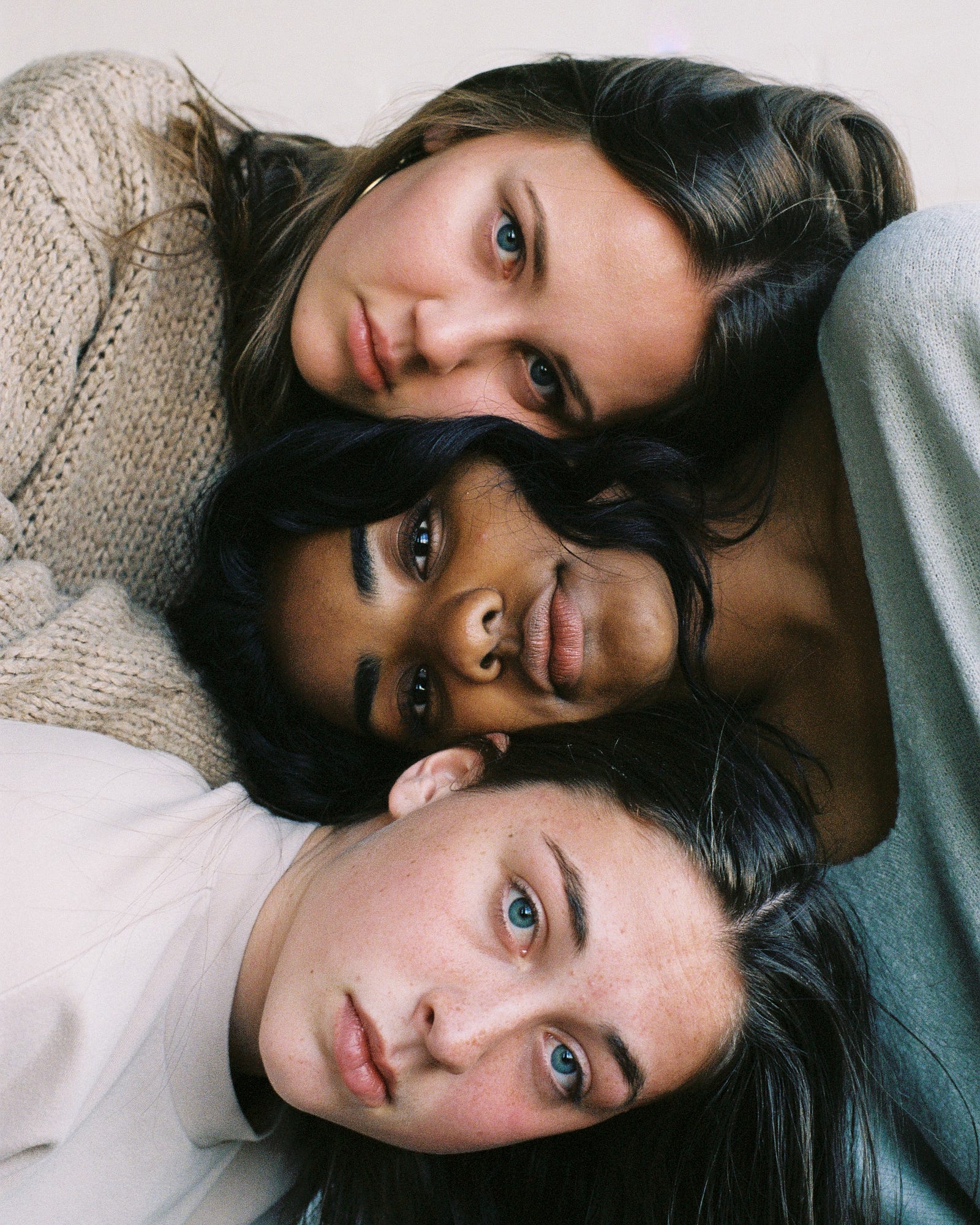 Three young women lie down, facing up to the camera. The top and bottom women (white) have bodies pointing to the left, while the middle (black) woman to the right. Racism has been America’s tragic flaw and that we continue to live with its ugly and explosive consequences. These consequences include huge health disparities.