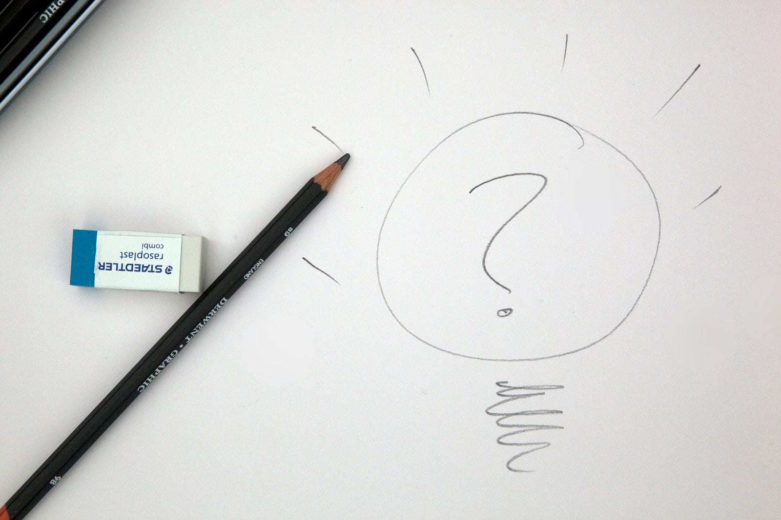 A pencil lies next to a circle with a question mark in its center.