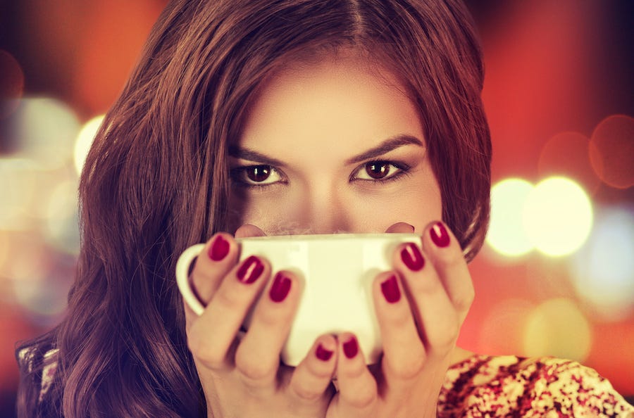 Coffee. Young beautiful Girl woman drinking Tea Cappuccino in trendy cafe shop. Beauty Model with Cup of Hot Beverage. Closeup portrait, warm colors. Human emotions positive facial expressions feeling