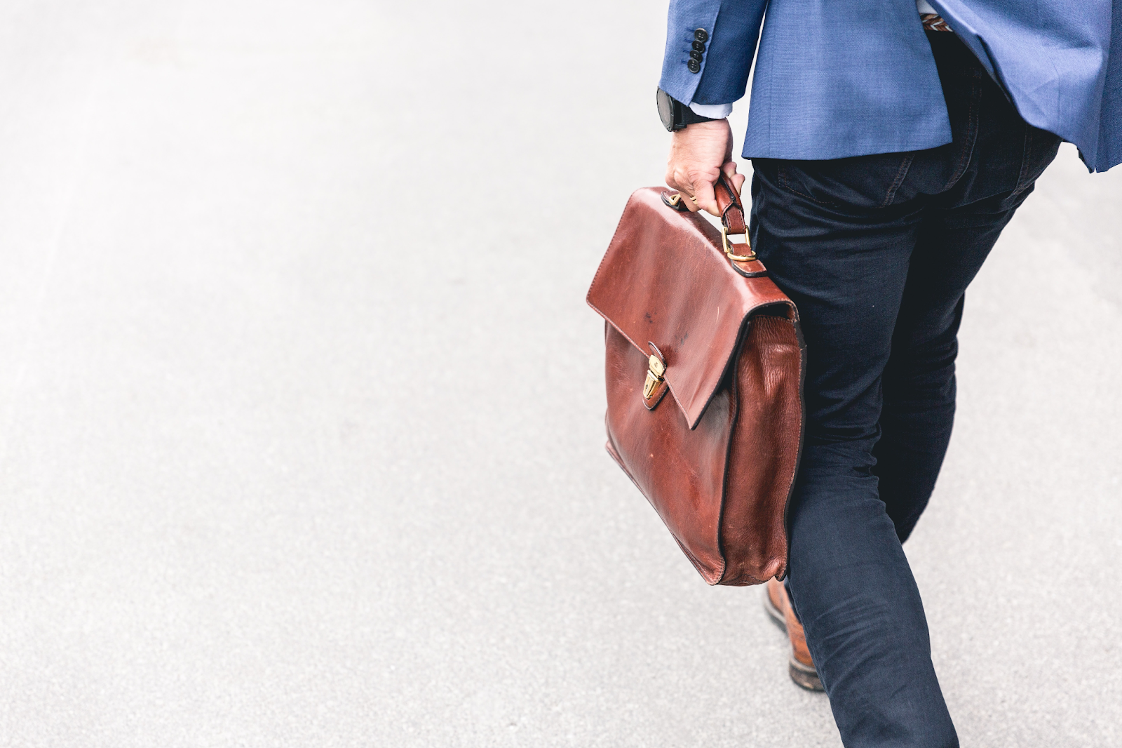 man holding leather briefcase and walking