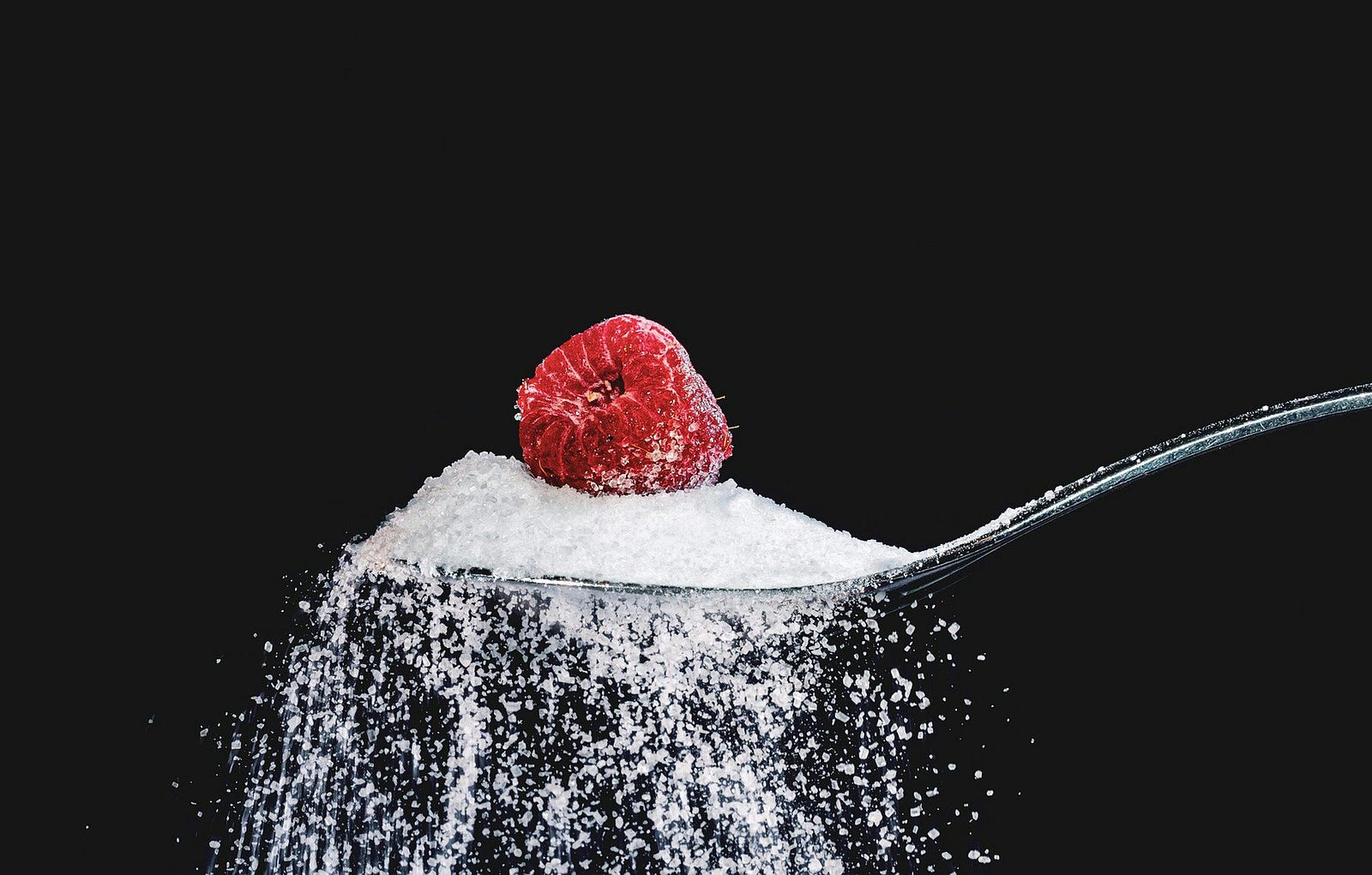 A heaping spoon of sugar (spilling over the sides) with a raspberry on top.