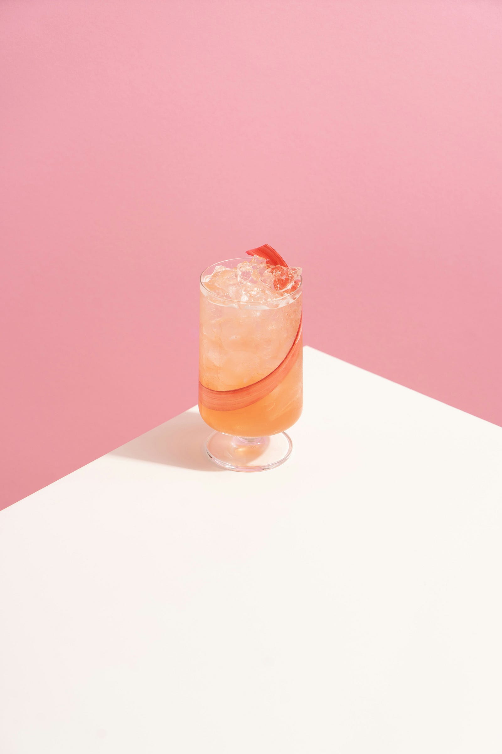 A glass of alcohol sits on the edge of a white table. Alcohol increases breast cancer risk.