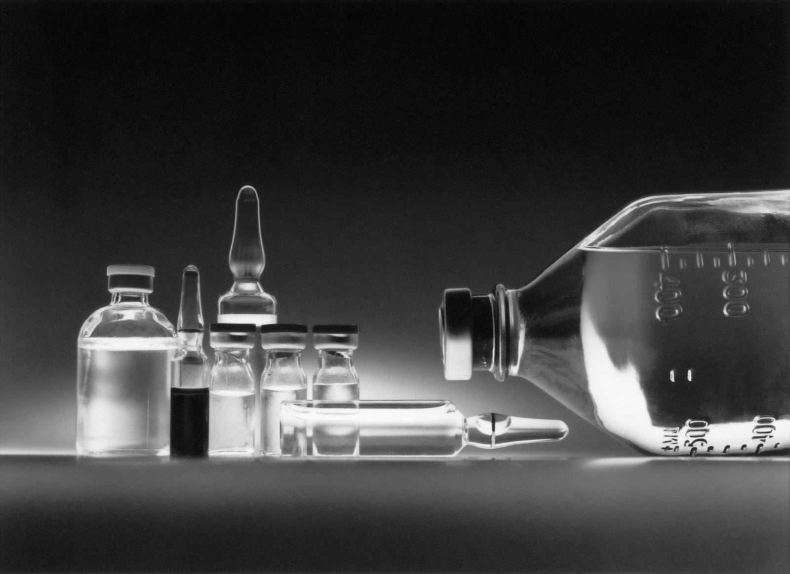 An array of glass bottles (vials and bottles for medicines) is depicted in black and white. New research shows how chemotherapy time for a lymphoma type can affect outcomes in women.