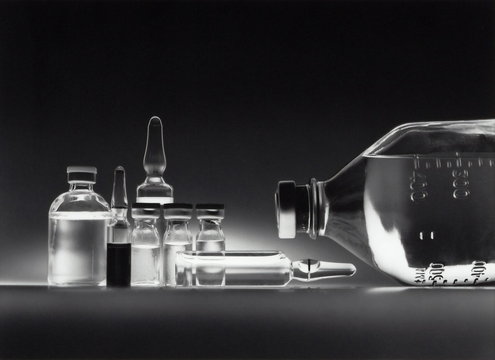 An array of glass bottles (vials and bottles for medicines) is depicted in black and white. New research shows how chemotherapy time for a lymphoma type can affect outcomes in women.