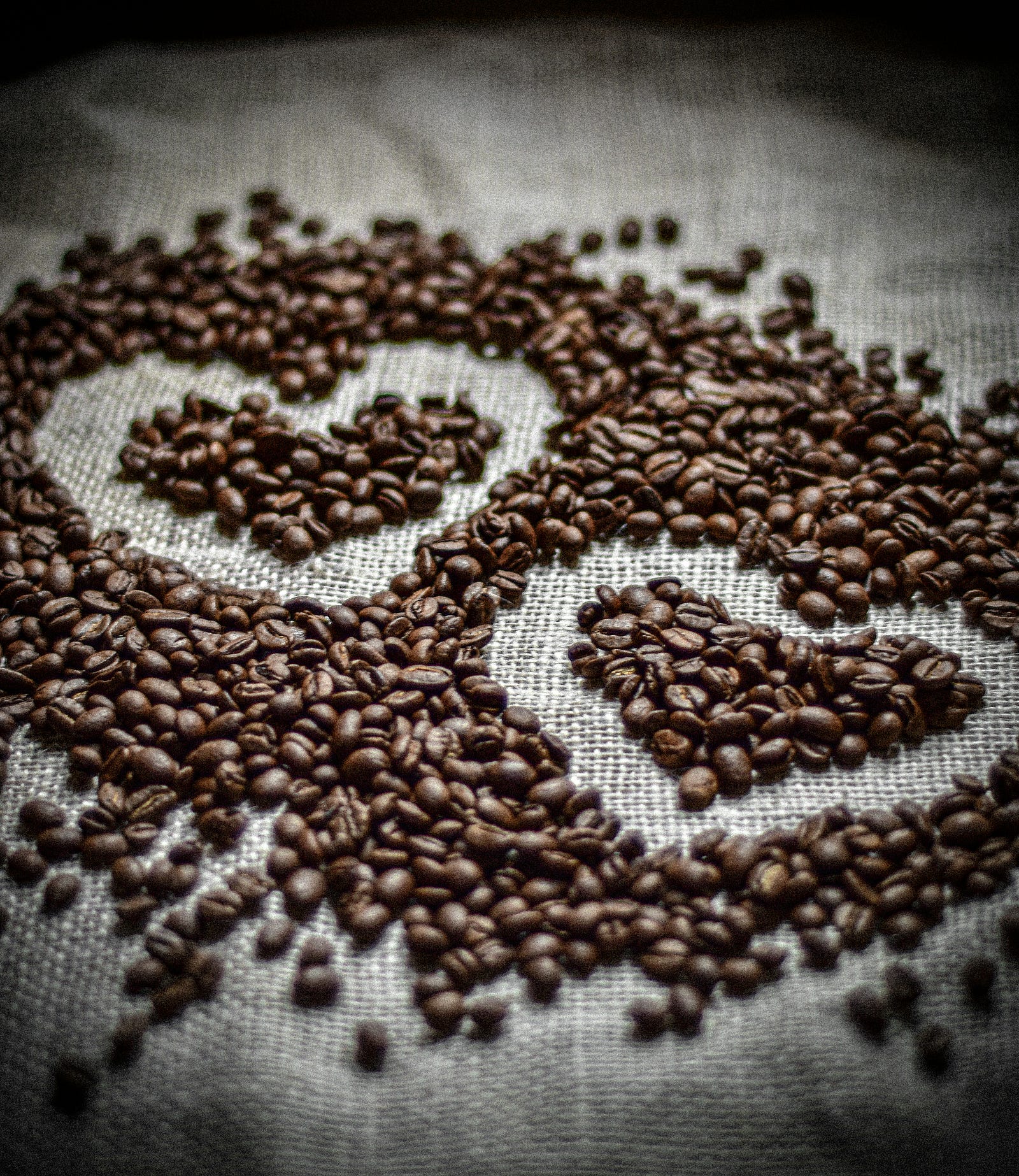 Dozens of coffee beans, with several creating the shapes of two hearts.