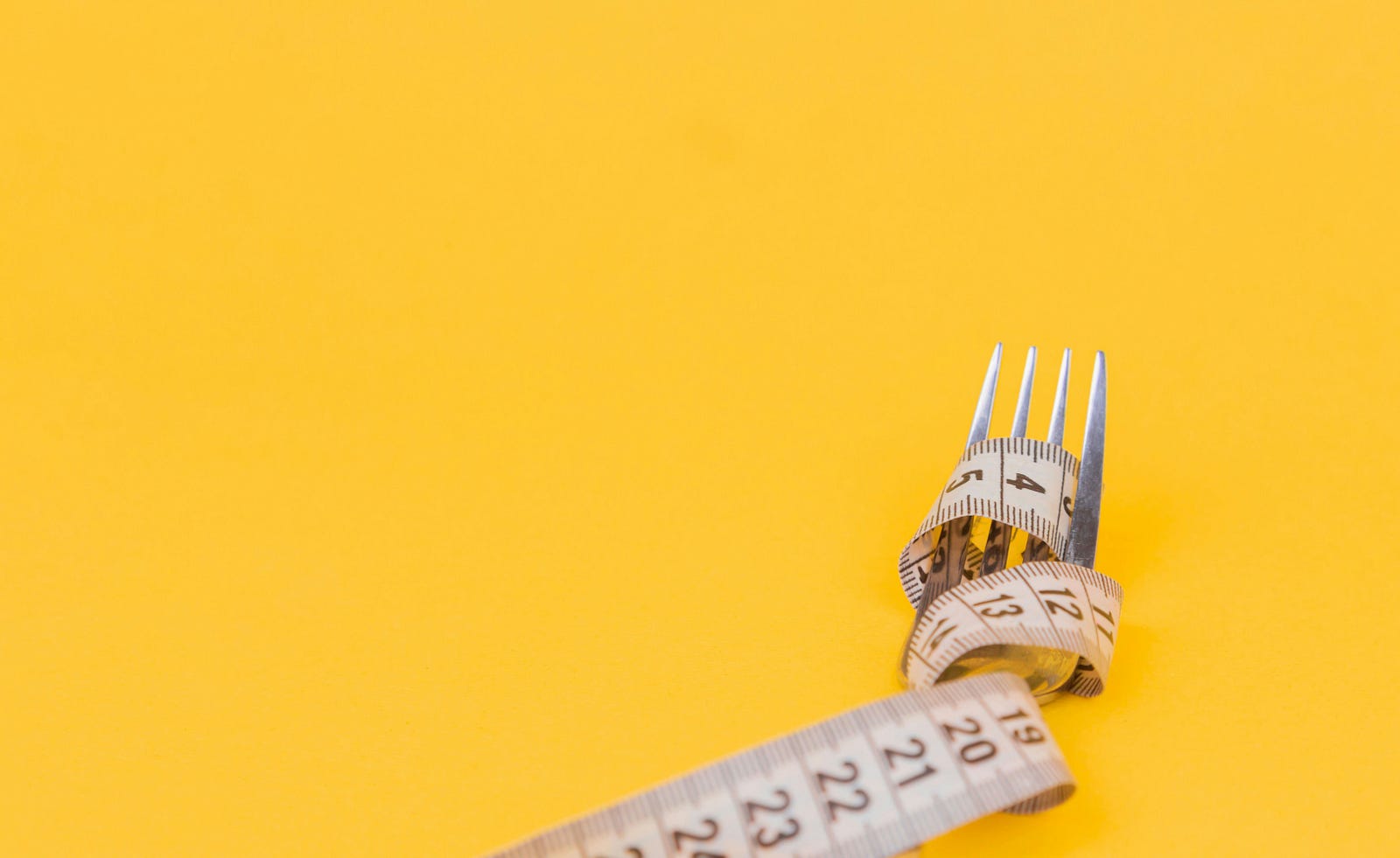 A paper tape measure is wrapped around a fork.