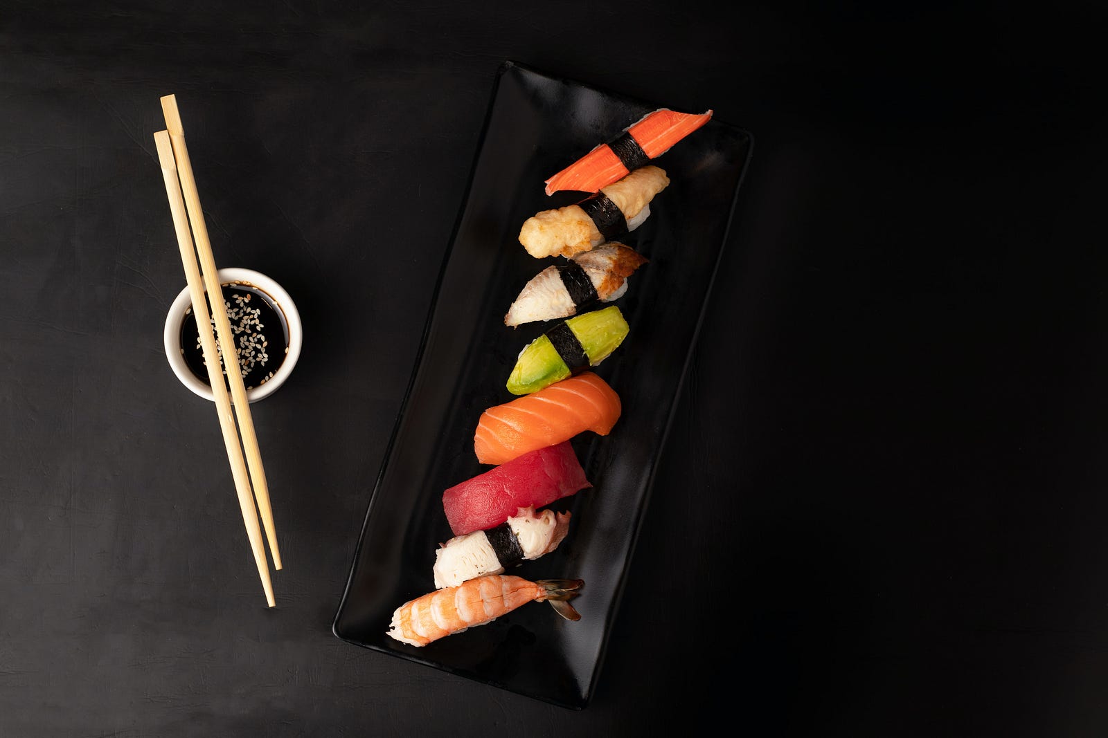 Pieces of sushi are aligned vertically on a narrow black plate. A pair of thin wooden chopsticks are perched on the left on a tiny plate. Japanese meals also tend to be well-balanced, featuring a variety of foods rich in nutrients. This emphasis on a balanced diet is a key factor in Japanese wellness. I discovered that the Japanese eat more slowly than their American counterparts.
