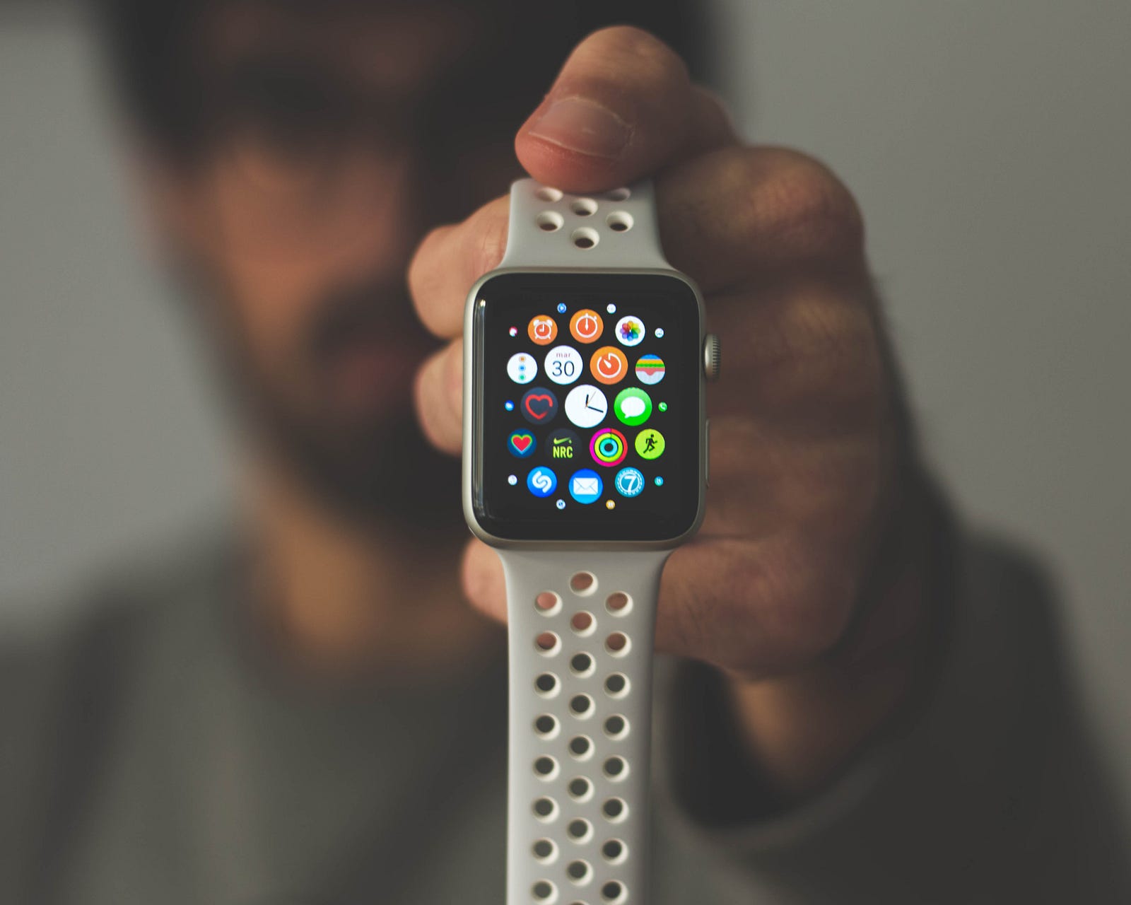 A person extends there hand (holding an Apple watch) towards us. Sleep trackers excel at providing general trends and patterns over time. They can be valuable tools for identifying consistent sleep deficiencies or irregularities.