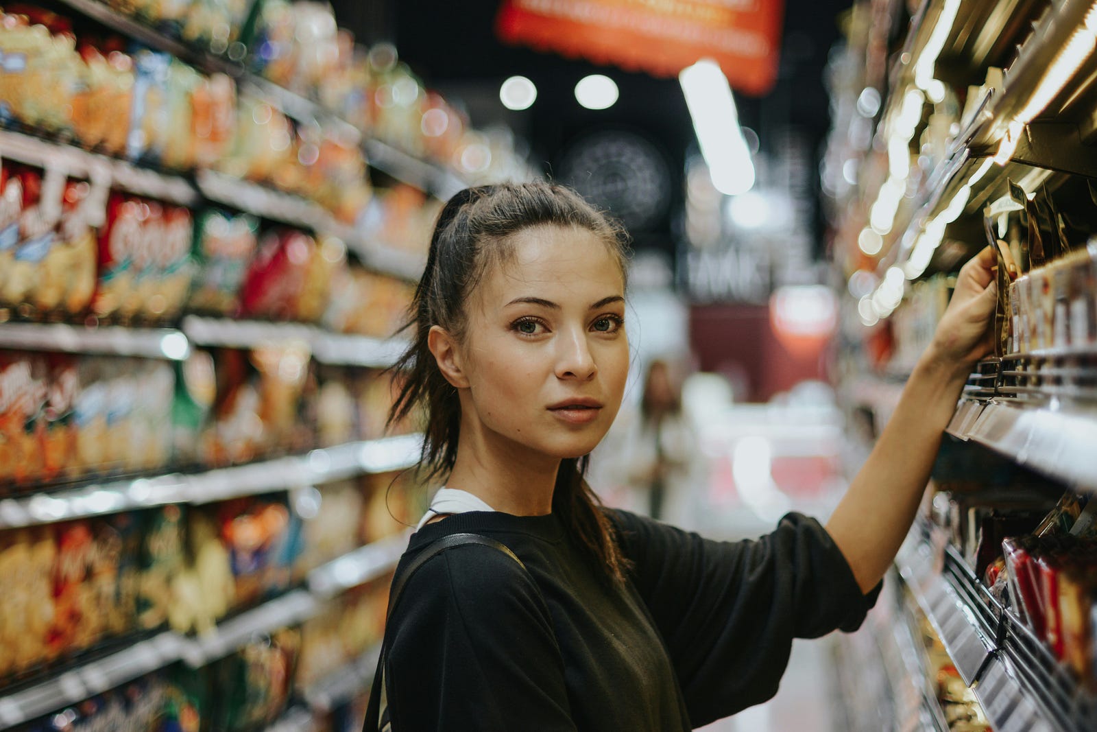 A woman reads food labels in a grocery store.