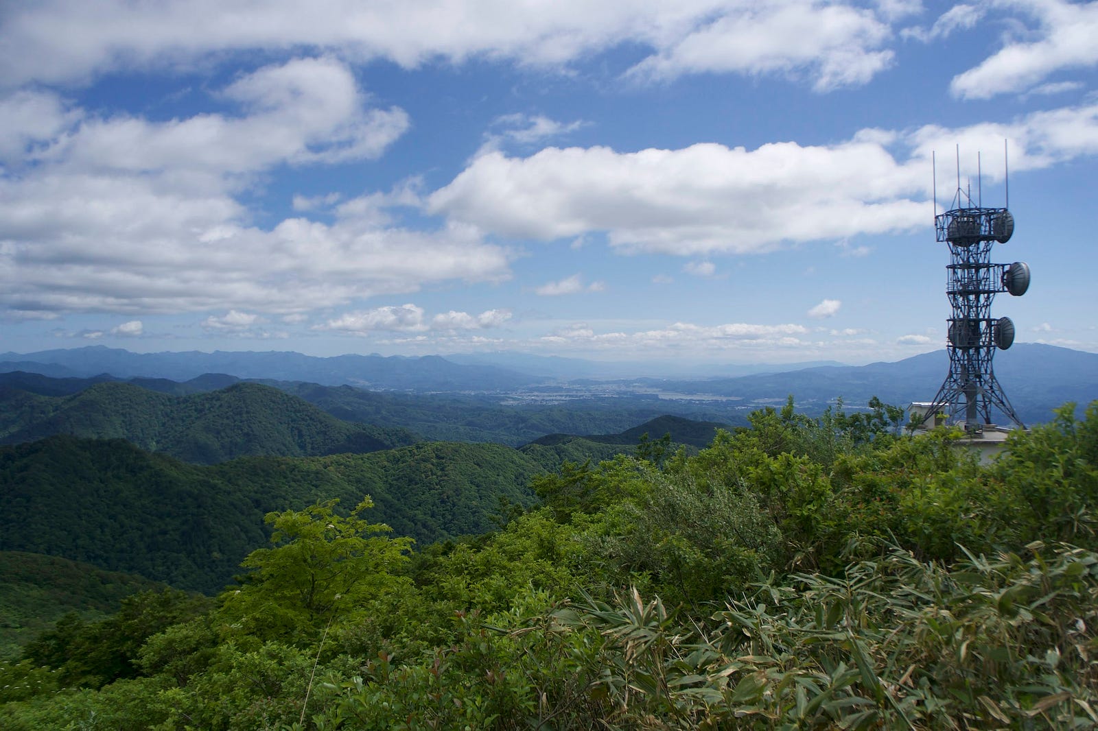 A cell tower stands atop Sankaku-yama, partially blocking Murayama Ha-yama but not the view towards the Mogami region of Yamagata.