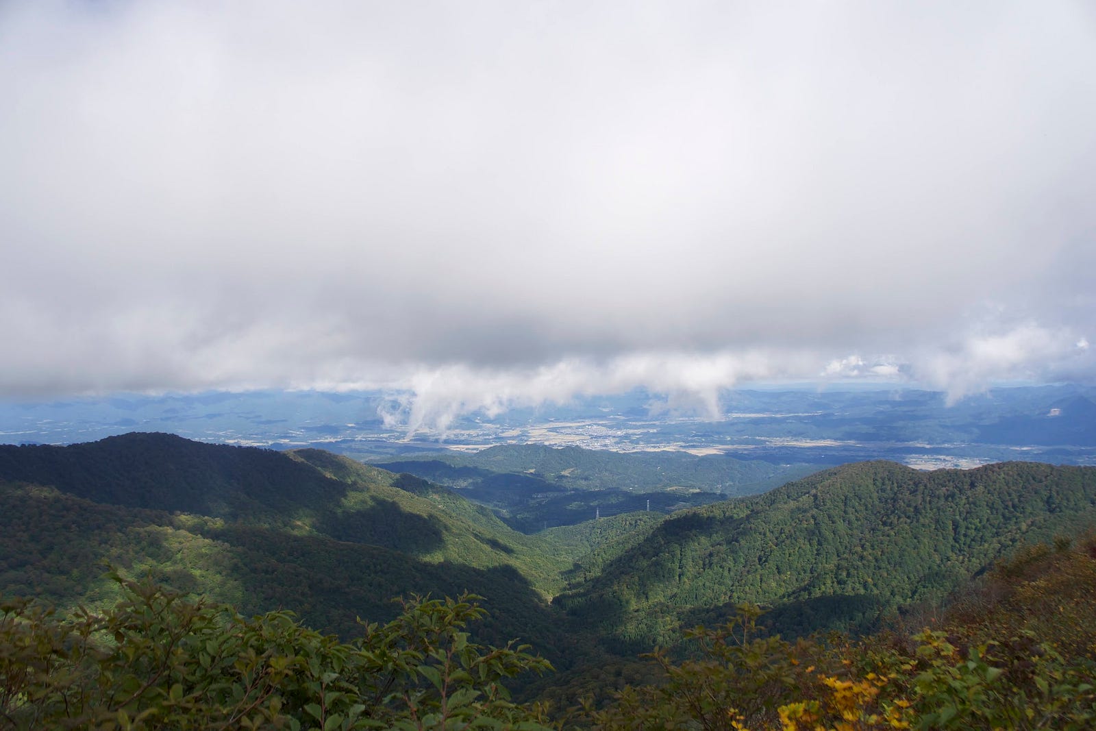 Obanazawa City sits under a cloudy sky in the distance, green mountains of Murayama Ha-yama in the foreground