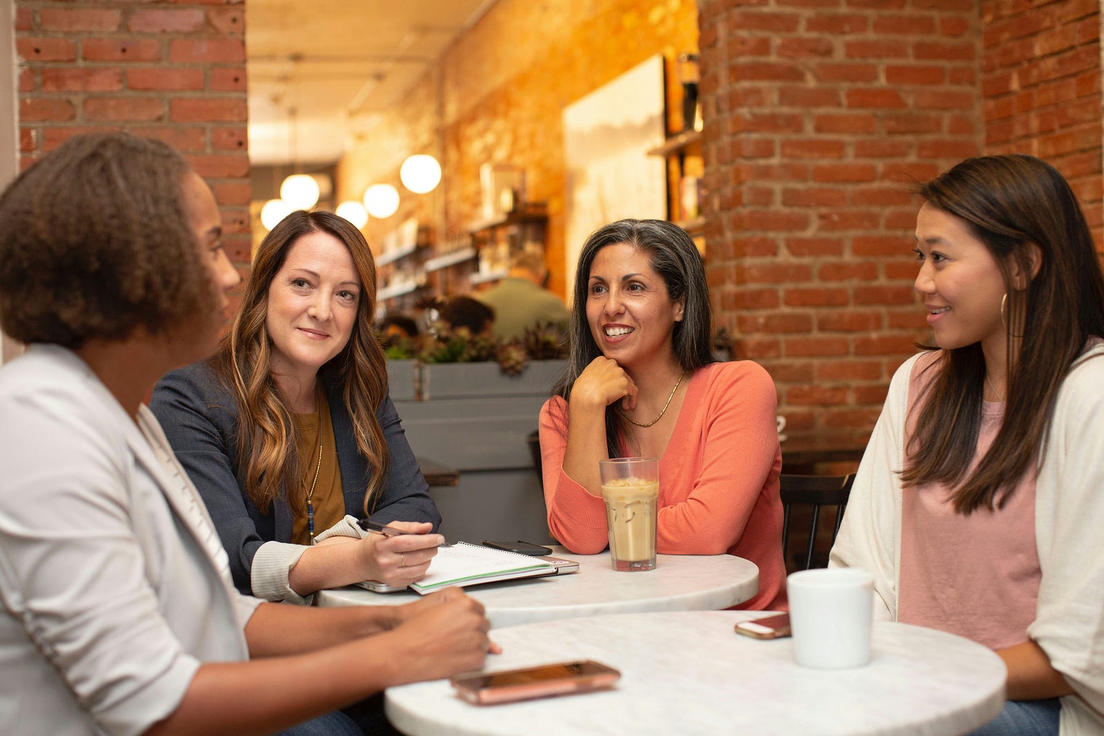 Four middle-aged women wit around a table chatting.