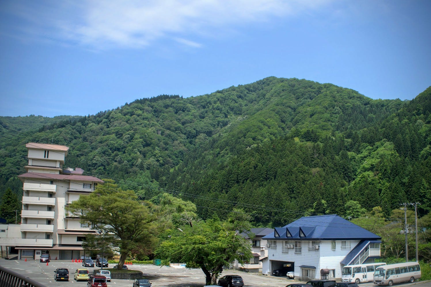 Two Ryokan (hotel) buildings in Semi Onsen in the foreground with the forested Kamewari-yama in the background.