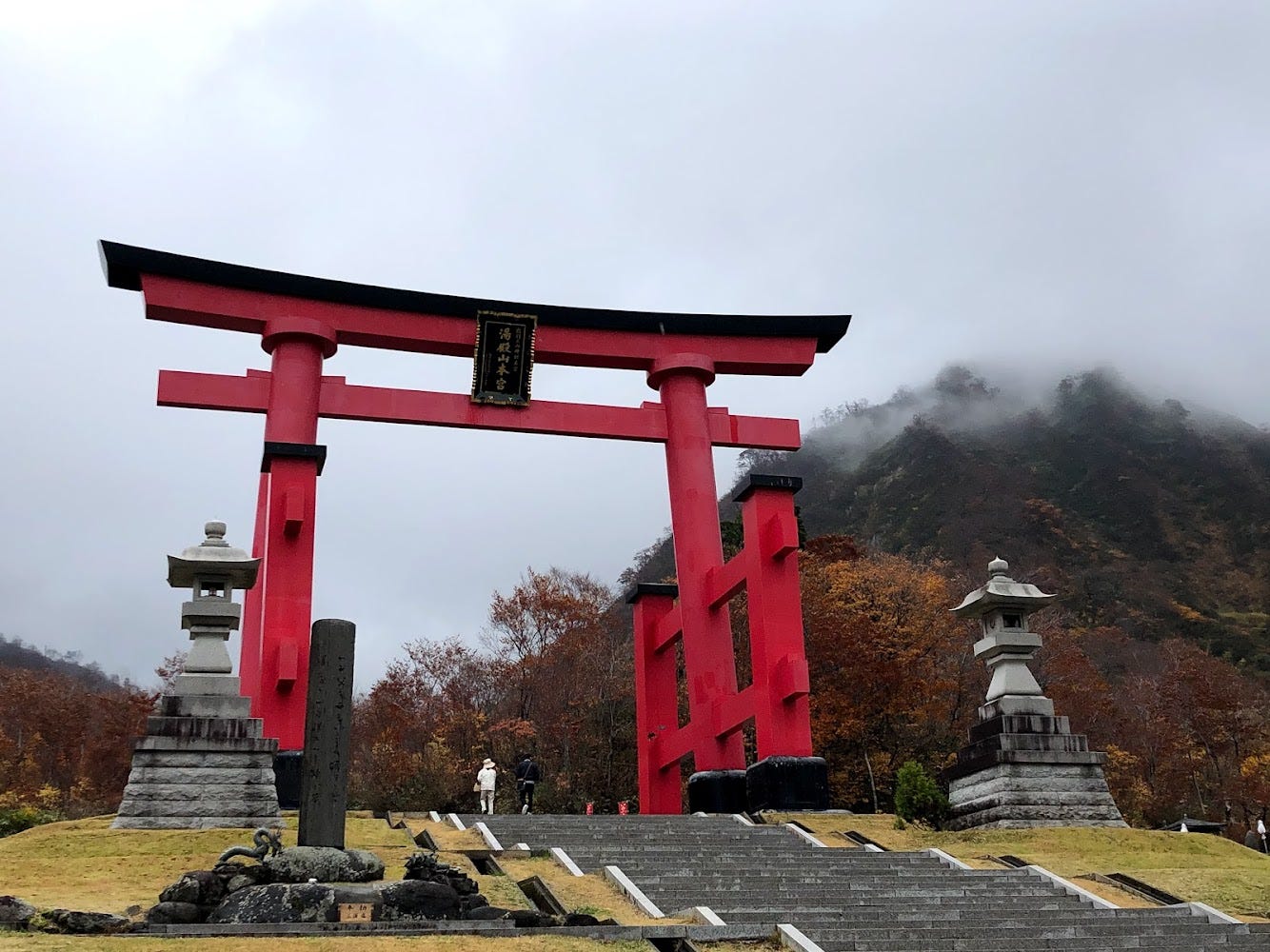 Mt. Yudono’s shrine gates tower over a visitor as the fog of autumn shrouds over a nearby mountain peak