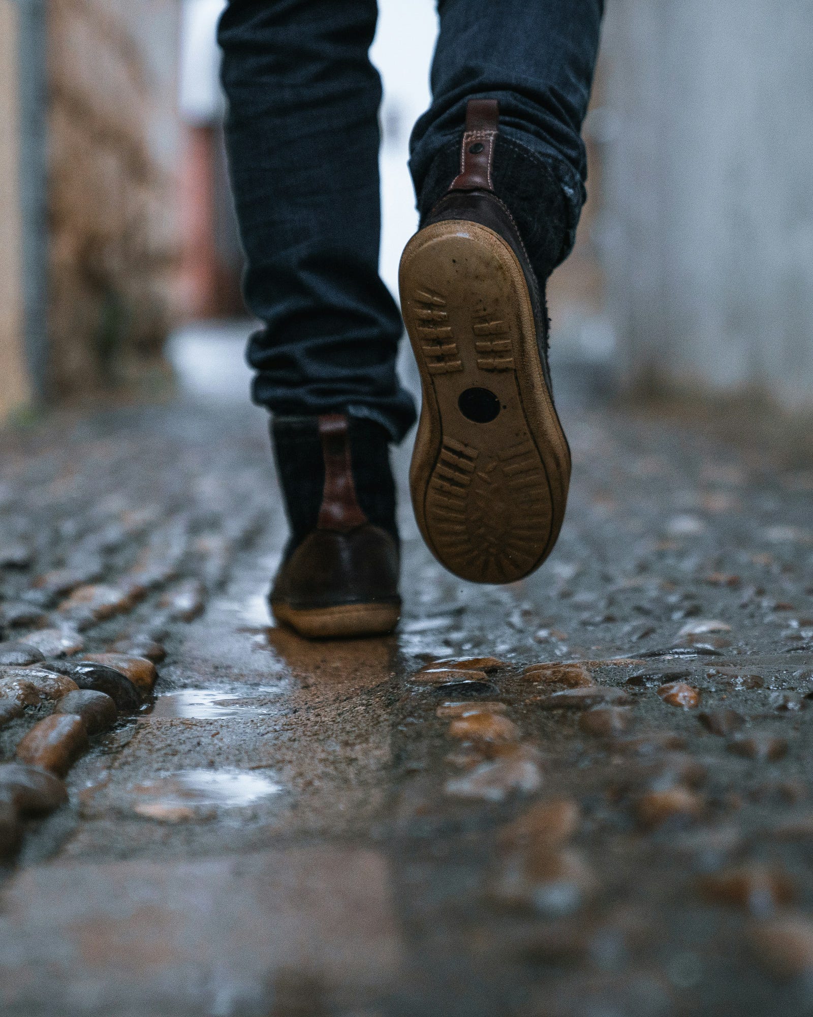 We see a person (from the knees down) walking away from us on pavement.