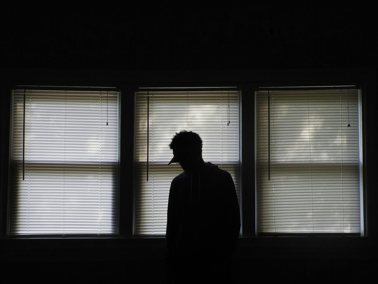 A man stands in front of three windows in a black and white image.