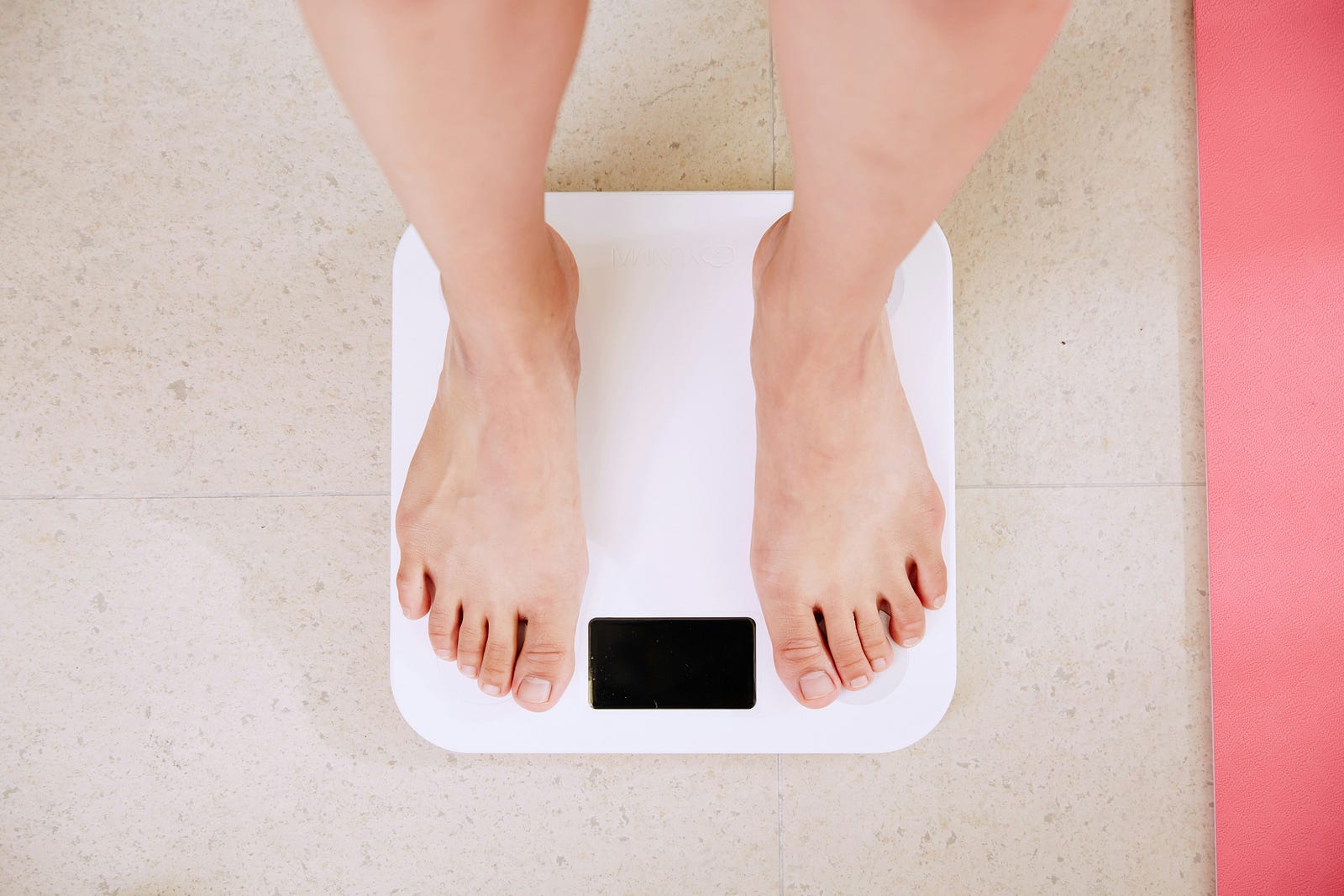 A person stands on a scale to weight themselves.