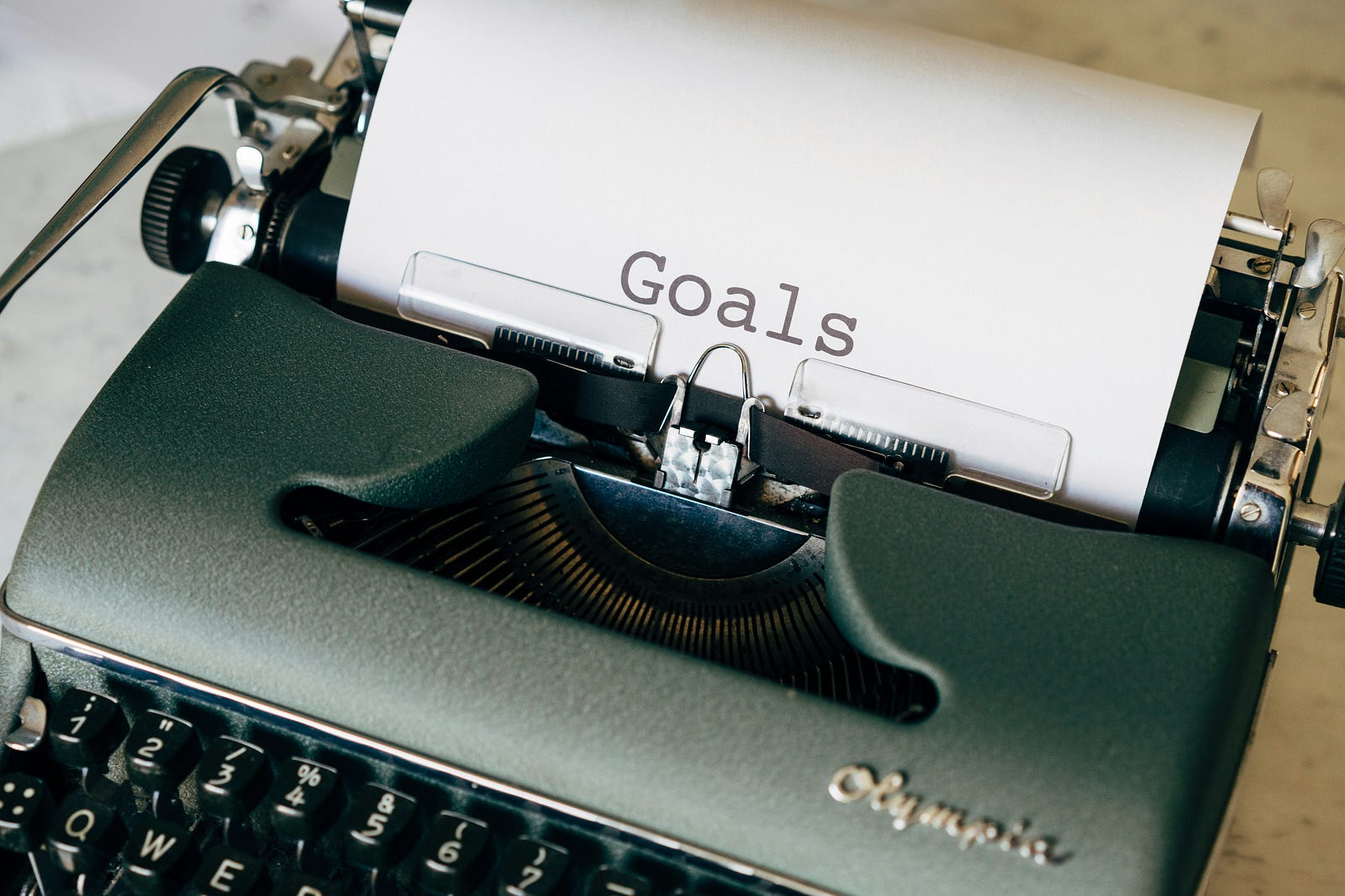 An old-fashioned typewriter has paper coming out, with the word “Goals” typed out.