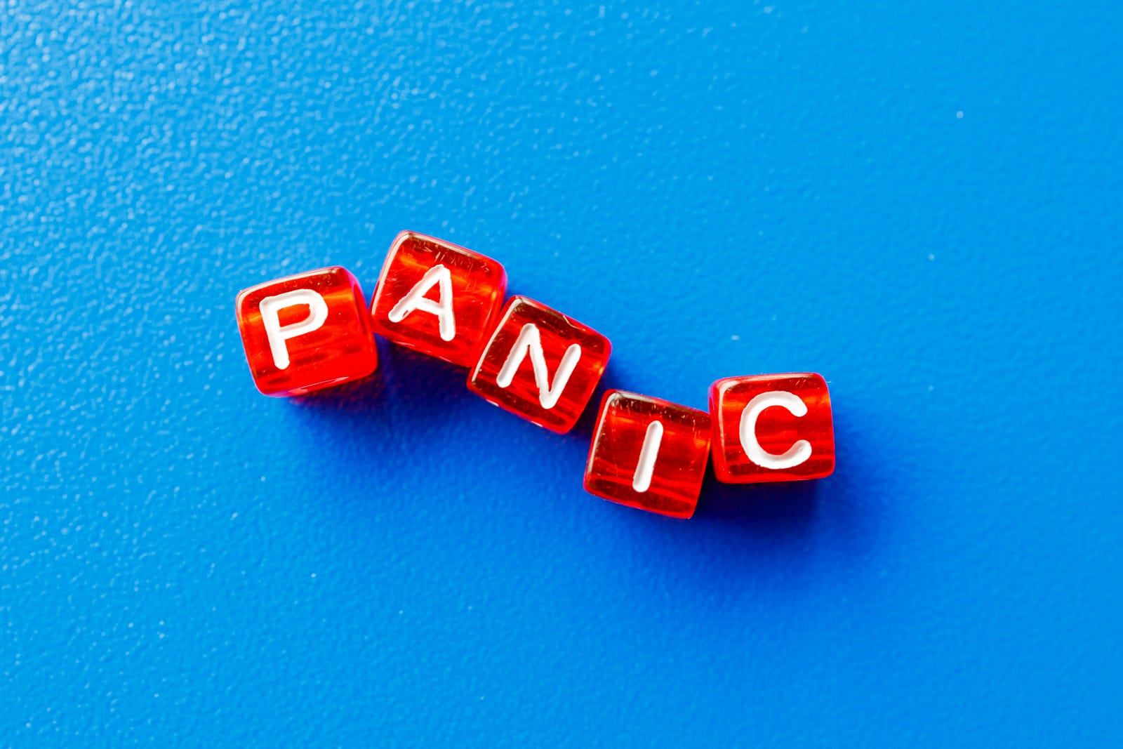The word PANIC spelled out in white letters on red dice. There is a blue background.