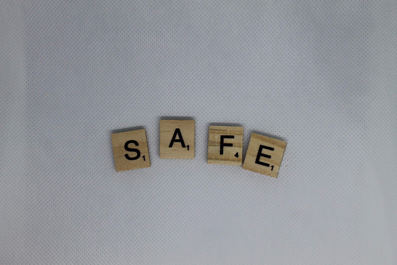 The word “SAFE” is spelled out in Scrabble tiles. White background. Petroleum jelly can help trap in moisture in the skin and is the basis for so-called skin slugging.