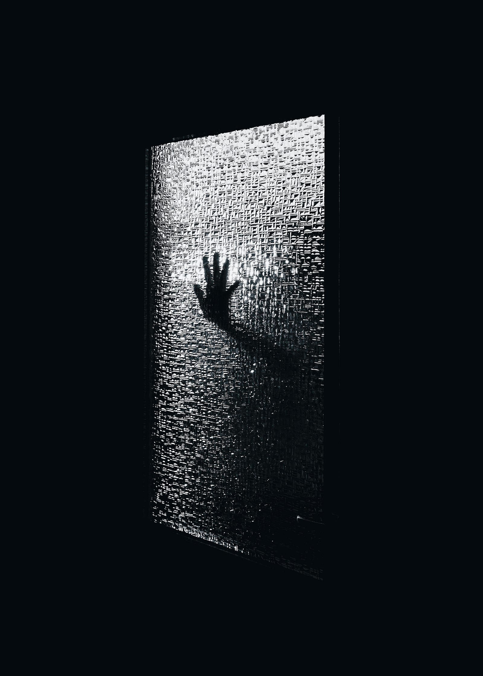 A black and white image of a hand pressing against a translucent window. We do not know the precise cause, but inherited genetics, biology, and life experiences (especially stressful ones) can play roles in generalized anxiety disorder.